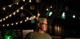 Ralph Philbaum sitting in a cantina, surrounded by colorful artwork and a bottle of tequila on the table.