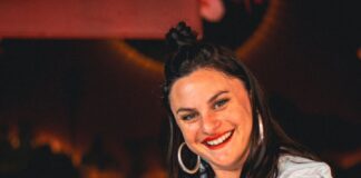 Rachel D'Acquisto, smiling, serving a glass of RayRay's Sonoran Tea, embodying the spirit of Tucson’s vibrant community.