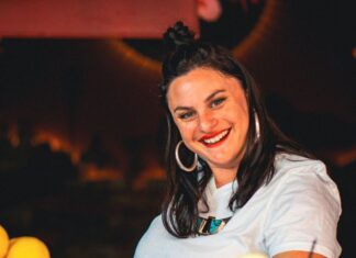 Rachel D'Acquisto, smiling, serving a glass of RayRay's Sonoran Tea, embodying the spirit of Tucson’s vibrant community.
