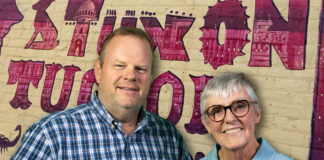 Jannie Cox and Tom Heath standing in front of a colorful Tucson mural celebrating the city's 250th anniversary
